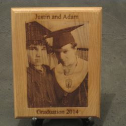 Wooden plaque with an engraved photo of two graduates, labeled "Justin and Adam, Graduation 2014.