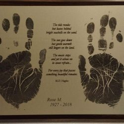 Plaque with two large handprints, a memorial poem, and the name Rose M. with the years 1927–2018 engraved.